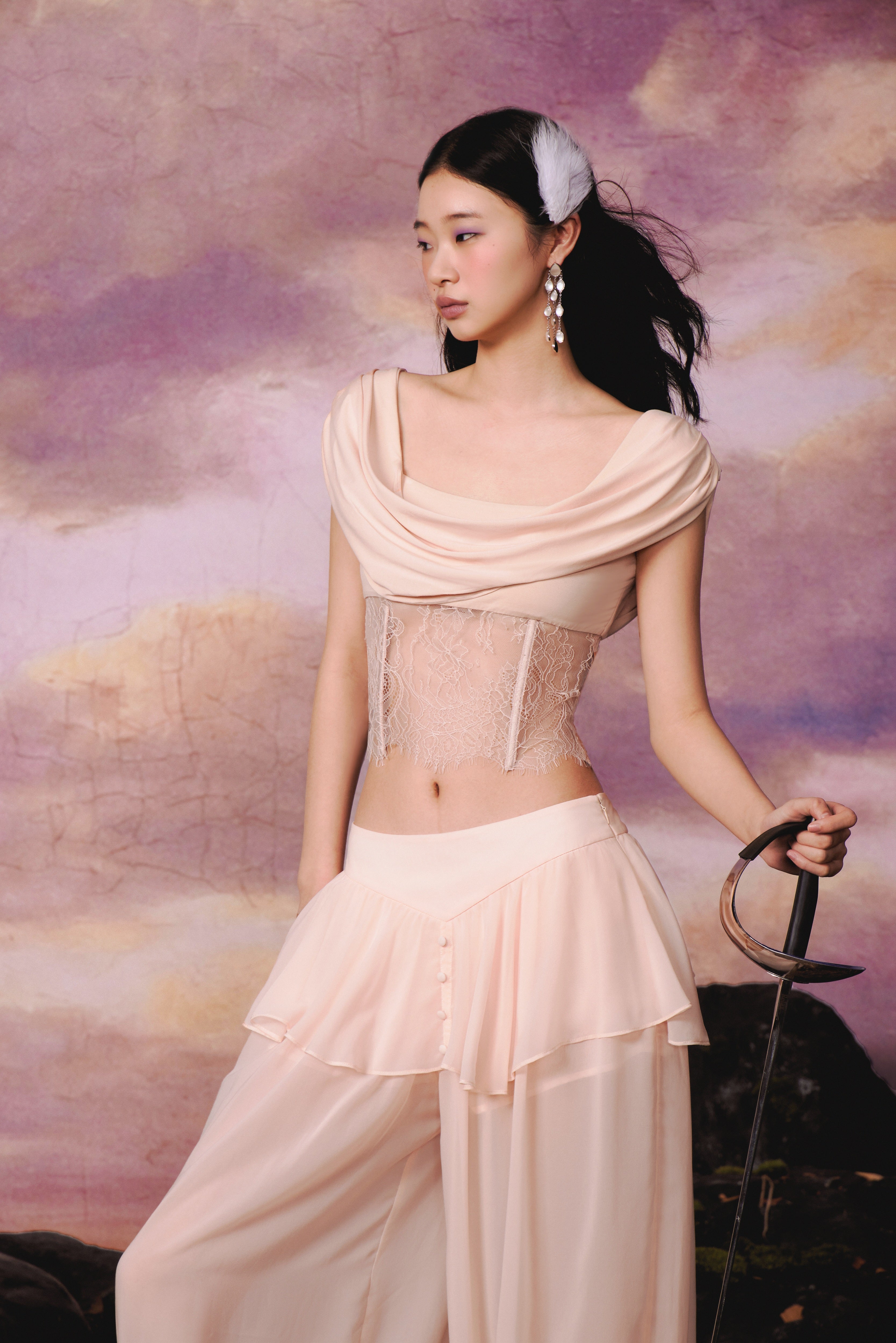 Woman in a beige outfit holding a sword against a purple sky background