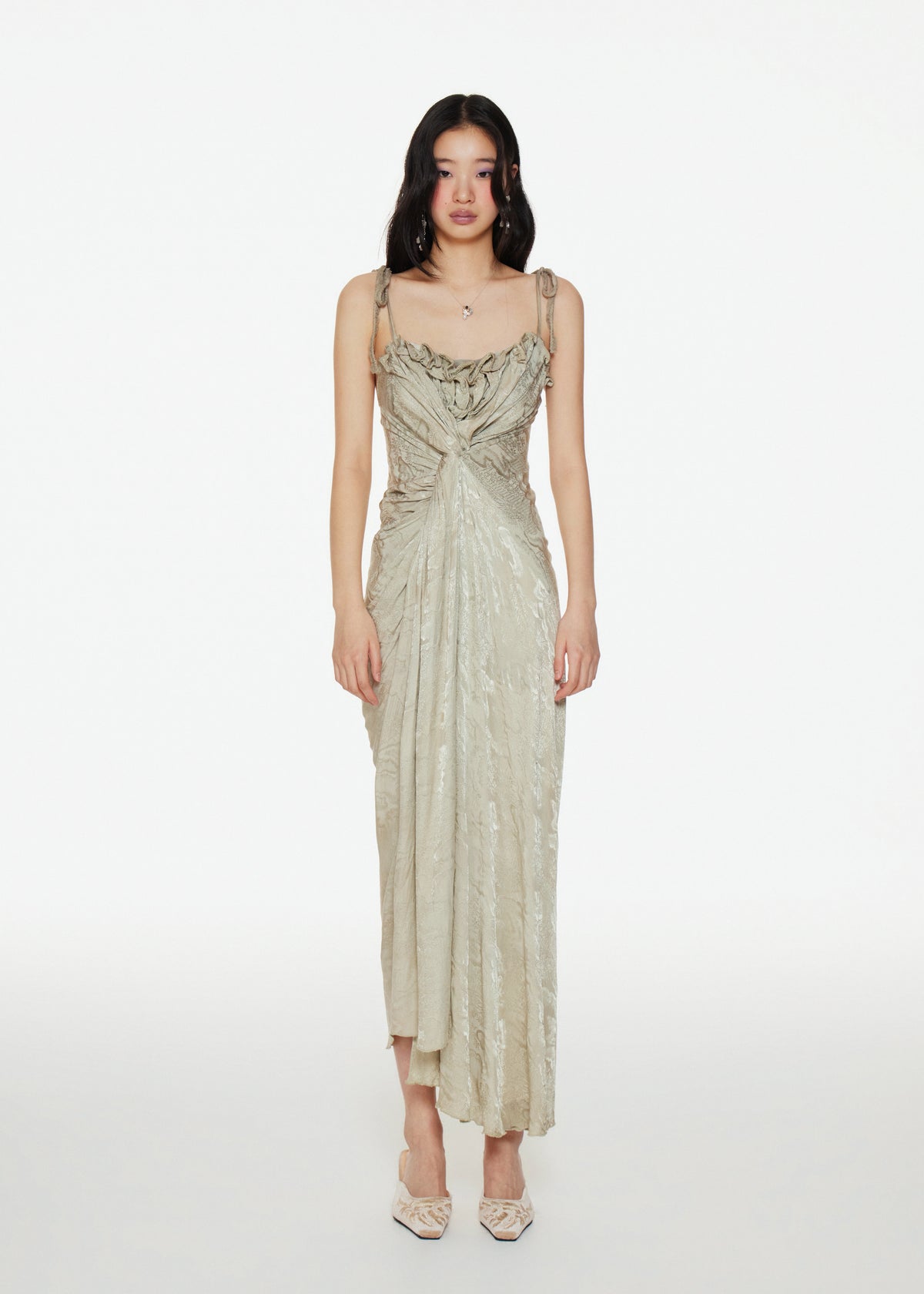Woman wearing a spaghetti-strap beige gown on a white background